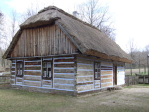 Drewniana chata kryta strzechą.